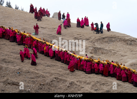 Une longue lignée de moines est un carrieng Tanka énorme d'un monastère de Labrang dans this page ministry strategy dans le Qinghai province Chine Banque D'Images