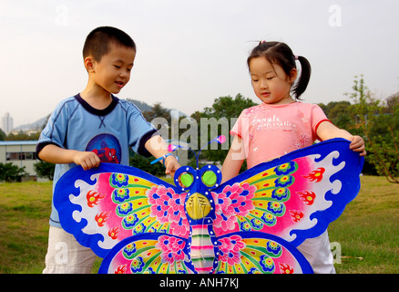 Une fille et garçon dans le parc jouer kite. Banque D'Images