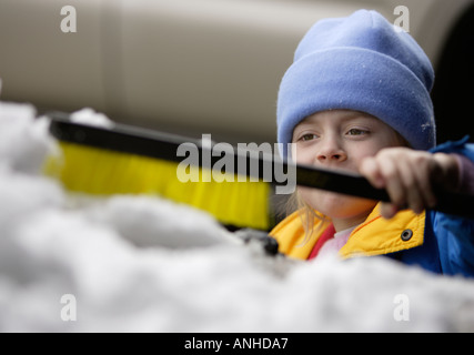 Enlever la neige de l'enfant à partir d'une voiture Banque D'Images