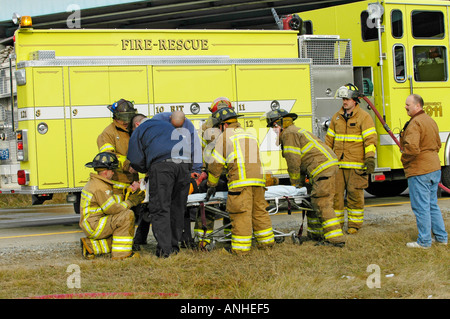 Les pompiers blessés à assister à l'égard des victimes d'accidents d'un chef sur l'accident automobile Banque D'Images