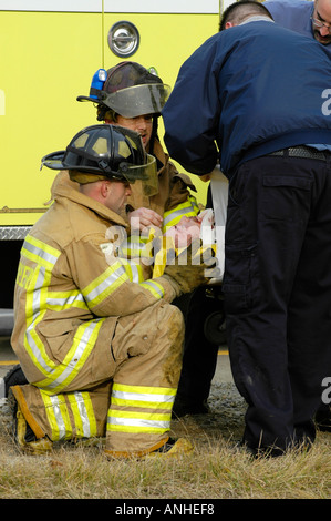 Les pompiers blessés à assister à l'égard des victimes d'accidents d'un chef sur l'accident automobile auto voiture Banque D'Images