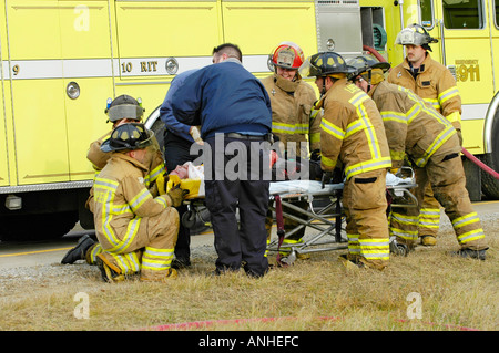 Les pompiers blessés à assister à l'égard des victimes d'accidents d'un chef sur l'accident automobile Banque D'Images