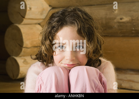 Fille assise avec la tête posée sur les genoux, smiling at camera Banque D'Images
