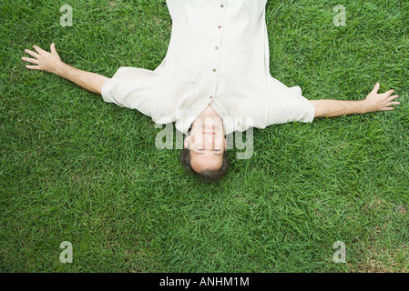 L'homme allongé sur le dos sur l'herbe, smiling at camera, vu à partir de juste au-dessus Banque D'Images
