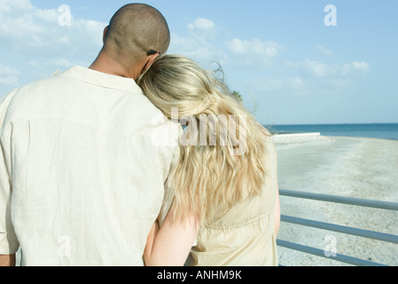 Couple standing arm in arm à la vue, à la tête de la femme sur l'épaule de l'homme, vue arrière Banque D'Images