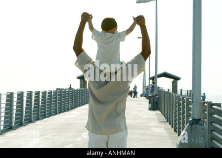 Père exerçant son fils sur les épaules, tenant les mains, vue arrière Banque D'Images