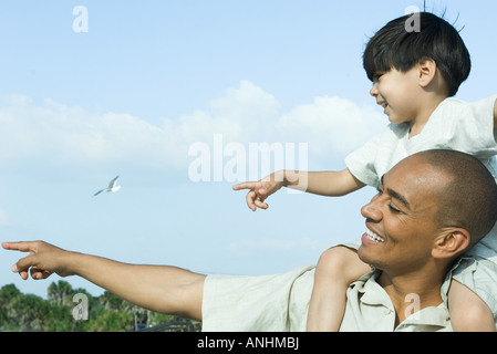 Père exerçant son fils sur les épaules, les deux pointant et à l'écart Banque D'Images