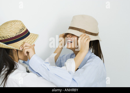 Deux jeunes amis chapeaux tirant sur les visages Banque D'Images