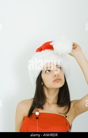 Teenage girl wearing Santa hat, looking up de pom-pom Banque D'Images