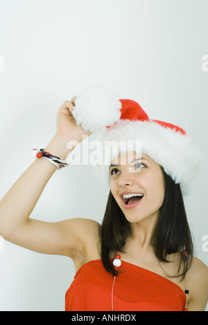 Teenage girl wearing Santa hat, regardant pom-pom en main, smiling Banque D'Images