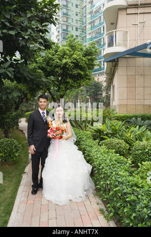 Bride and Groom standing dans résidence verdoyante, pleine longueur portrait Banque D'Images