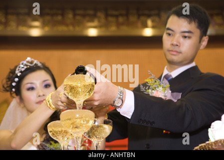 Couple pouring champagne into champagne verres ensemble empilés Banque D'Images