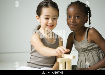 Deux filles assis, jouant avec des blocs, un smiling at camera Banque D'Images