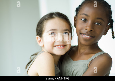 Deux jeunes amis féminins enlacés, l'un smiling at camera Banque D'Images