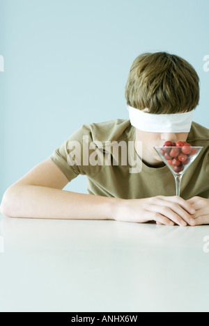 Jeune homme portant bandeau, verre odeur plein de tomates cerises Banque D'Images