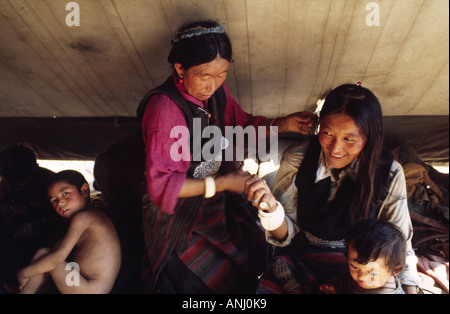 Famille des pèlerins tibétains, mère coiffant les cheveux de sa fille dans le style traditionnel, dans leur tente au Kalachakra Festival, Bodha Gaya, Inde Banque D'Images