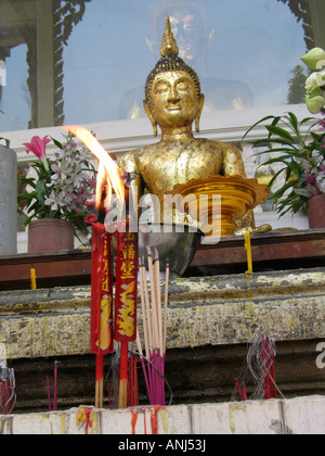 Bougies, encens et statue bouddhiste dans un temple à Bangkok, Thaïlande. Banque D'Images