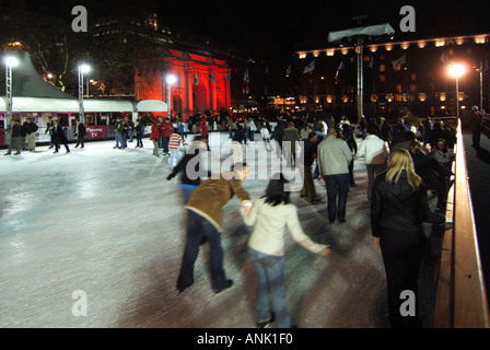 Motion Blur skateurs les gens sur la patinoire à Noël illuminé En hiver, patinoire West End Marble Arch allumée en rouge Projecteurs Londres Angleterre Royaume-Uni Banque D'Images