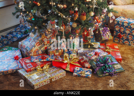 Papier de Noël enveloppant des cadeaux dispersés autour de la base d'un arbre de Noël décoré intérieur salon intérieur Essex Angleterre Royaume-Uni Banque D'Images
