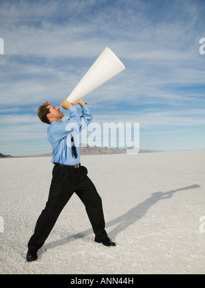 Businessman yelling into megaphone, Salt Flats, Utah, United States Banque D'Images