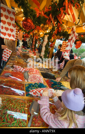 Close up vertical de personnes aident eux-mêmes à bonbons à partir d'un Pick 'n Mix décroche à un traditionnel marché de Noël. Banque D'Images