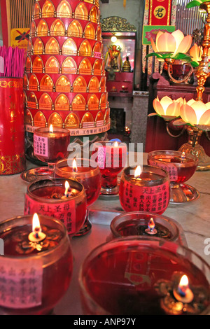 Autel dans un temple chinois avec différentes offres et des bougies Banque D'Images