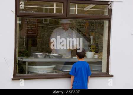 Petit garçon regardant le boulanger préparer la nourriture derrière la fenêtre de la boulangerie Banque D'Images