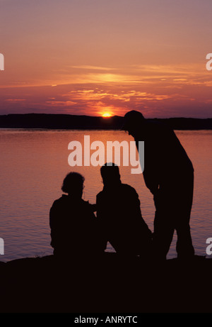 Trois hommes qui se profile en face de Seascape colorés et le coucher du soleil de l'archipel W Suède sweden Banque D'Images