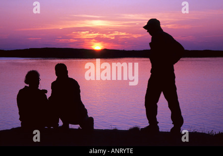 Trois hommes qui se profile en face de Seascape colorés et le coucher du soleil de l'archipel W Suède sweden Banque D'Images