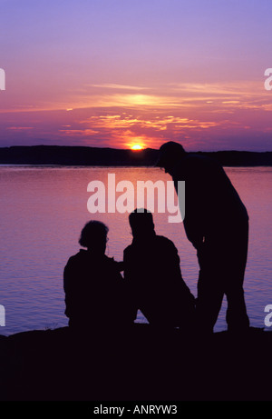 Trois hommes qui se profile en face de Seascape colorés et le coucher du soleil de l'archipel W Suède sweden Banque D'Images