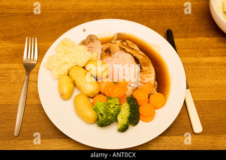 "Viande britannique traditionnel et deux veg' rôti de porc le dimanche soir sur plaque blanche sur une table en bois avec couteau et fourchette, UK Banque D'Images
