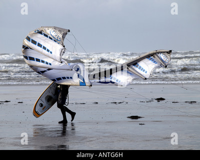 Kite surfer, aux prises avec son cerf-volant sur un jour très venteux, après être sorti de la mer. Banque D'Images
