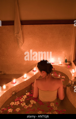 Jeune femme de prendre de bain avec pétales de fleurs Banque D'Images
