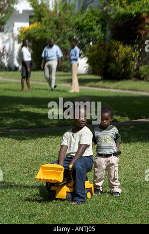 Les enfants africains locaux jouant avec soeur plus âgée assise sur Little Brother's Toy chariot. Il est assez. Banque D'Images