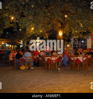 Les gens de manger en extérieur dans un square sous un arbre de nuit à une taverne dans la ville de Skopelos île de Skopelos Sporades du Nord Grèce Banque D'Images