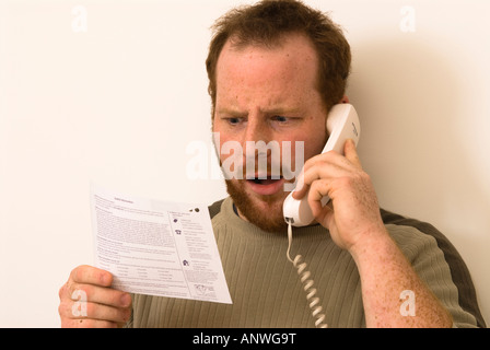 L'homme sur le téléphone en question des éléments sur ses relevés bancaires montrant surpris surprise ou d'horreur Banque D'Images