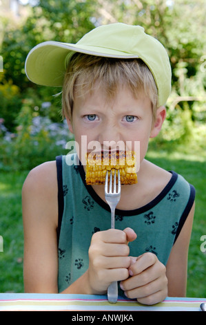 Garçon, 11 ans, est en train de manger du maïs maïs grillés ou frits Banque D'Images