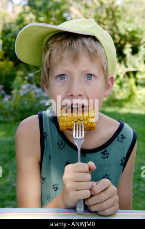 Garçon, 11 ans, est en train de manger du maïs maïs grillés ou frits Banque D'Images