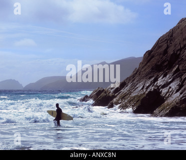 Surfer à gué à travers le surf à Slea Head Irlande Banque D'Images