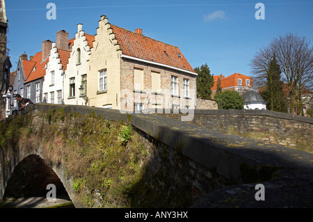Belgique, Bruges. Un couple d'oeil sur l'un des plus anciens ponts traversant l'un des nombreux canaux. Banque D'Images