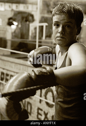 Une forte moody noir et blanc portrait d'un jeune boxeur de porter ses gants de boxe et debout dans le coin du ring. Banque D'Images