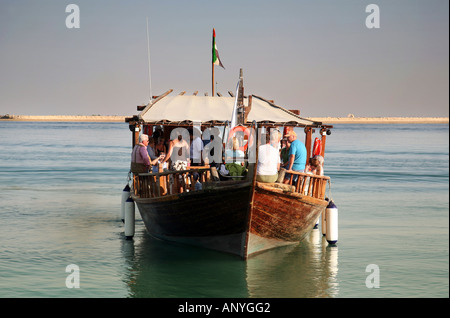 Vue frontale d'un dhow traditionnel en bois à flot avec un groupe de touristes à bord, Abu Dhabi, UAE Banque D'Images