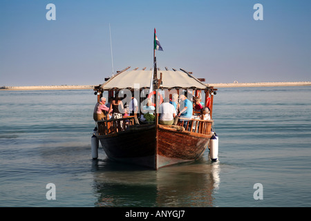 Vue frontale d'un dhow traditionnel en bois à flot avec un groupe de touristes à bord, Abu Dhabi, UAE Banque D'Images