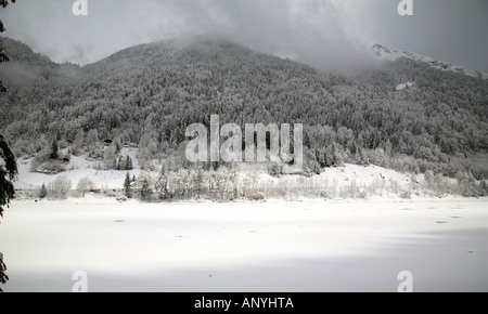 Lac de Montriond, partiellement gelés en hiver, avec de la neige tout autour, Alpes, France Banque D'Images