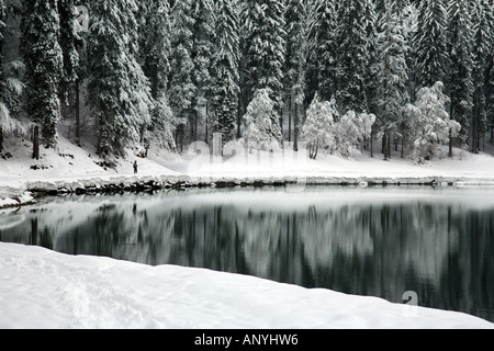 Pêcheur solitaire, Lac de Montriond, partiellement gelés en hiver, la neige tout autour, Alpes, France Banque D'Images