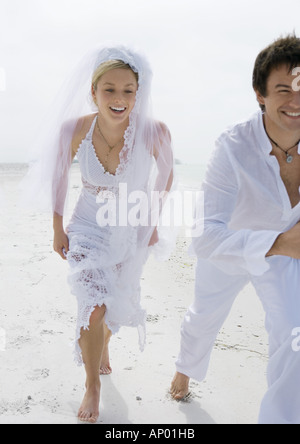 Bride and Groom running on beach Banque D'Images