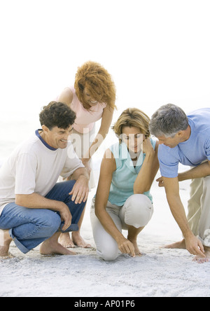 Deux couples matures crouching on beach Banque D'Images