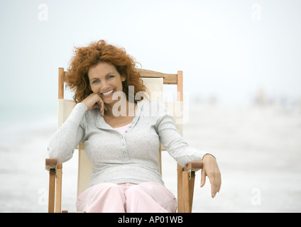 Femme assise dans la chaise de plage, smiling Banque D'Images