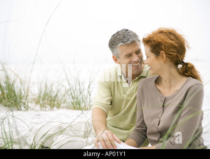 Mature couple sitting on beach Banque D'Images