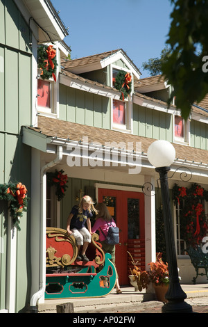 L'ILLINOIS Noël Long Grove magasin de détail dans le quartier commerçant pittoresque de fille saute sur traîneau couronnes porche porte femme Banque D'Images